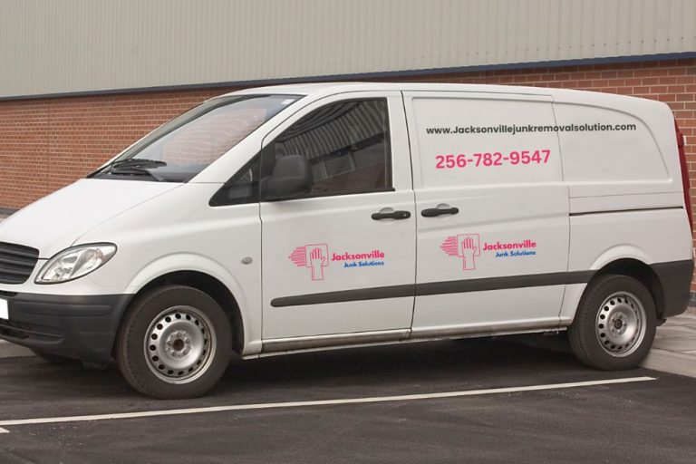 A white van with pink and blue text promoting a junk removal service located in Jacksonville, Florida.