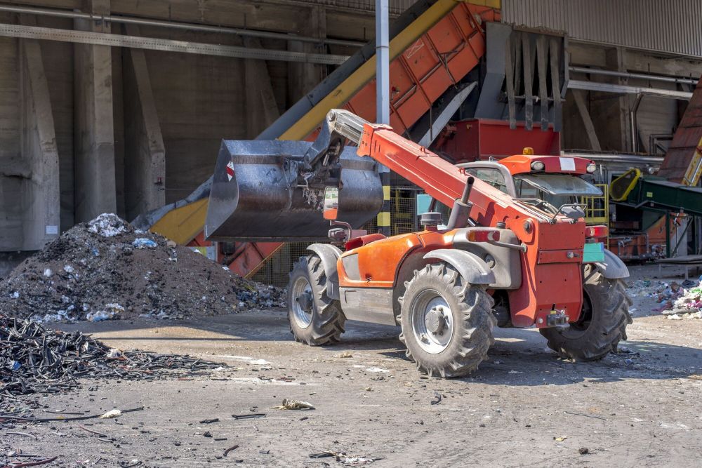 A forklift is engaged in clearing a pile of garbage at a construction and renovation site in Jacksonville, FL.